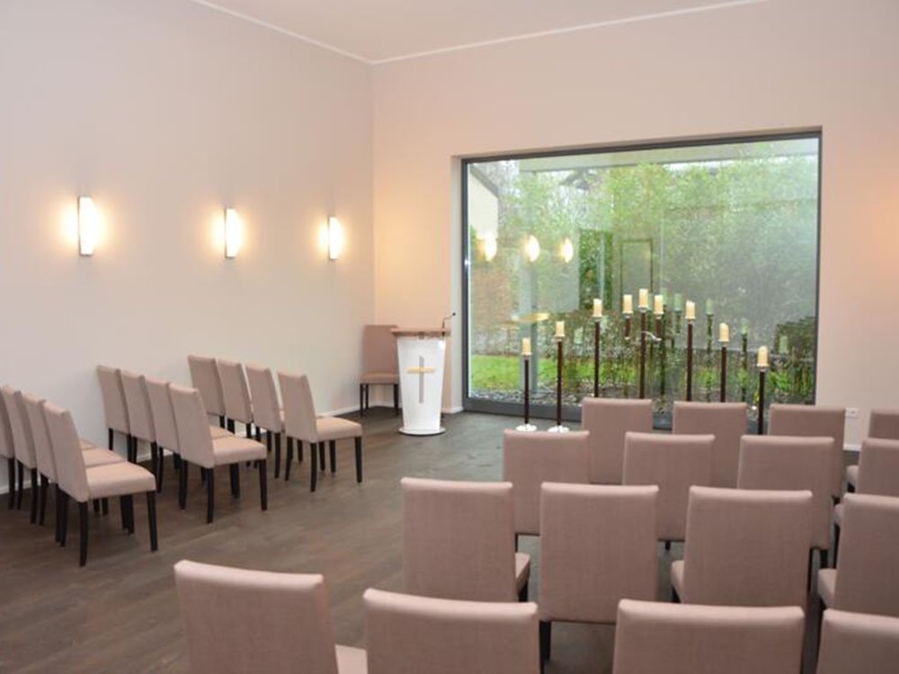 Eigene Trauerhalle für Trauerfeiern – Müther-Bestattungen Helle Trauerhalle mit Bestuhlung und Rednerpult bei Müther in Gütersloh