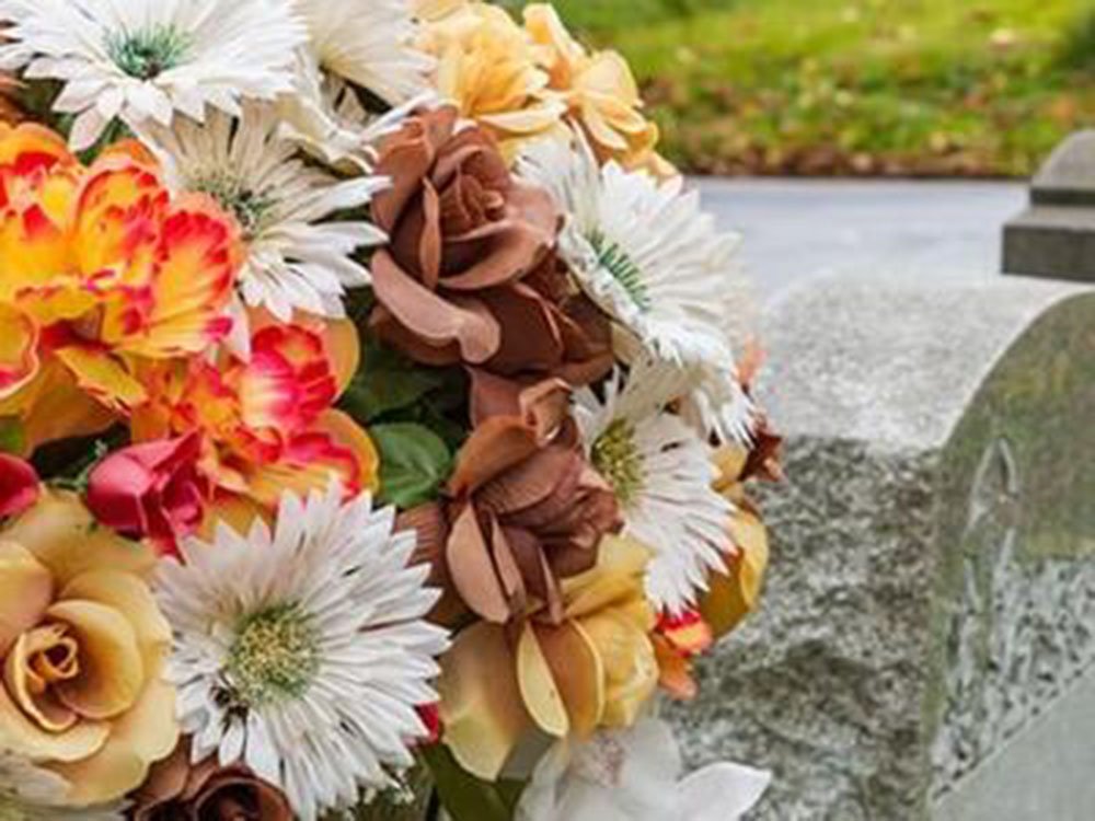 Trauerfloristik & Grabgestaltung – Müther-Bestattungen Farbenfroher Blumenstrauß mit Rosen und Gerbera an einem Grabstein